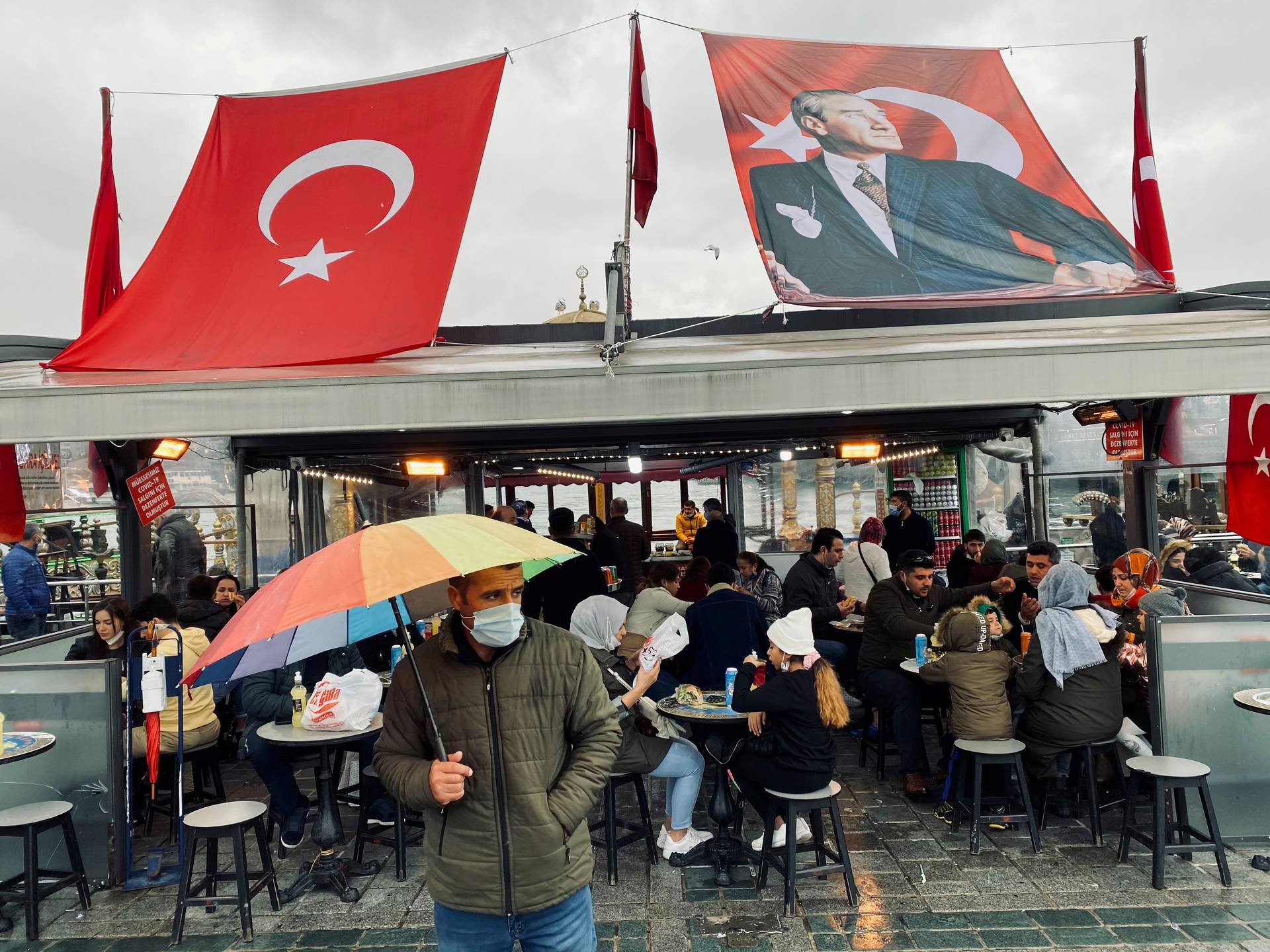 FILE PHOTO: Man wearing a protective mask stands in front of a fish and bread restaurant in Istanbul