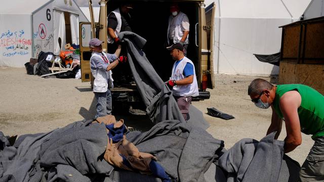 Workers remove blankets used by migrants during a police operation to evacuate a migrants' makeshift camp at the Greek-Macedonian border near the village of Idomeni