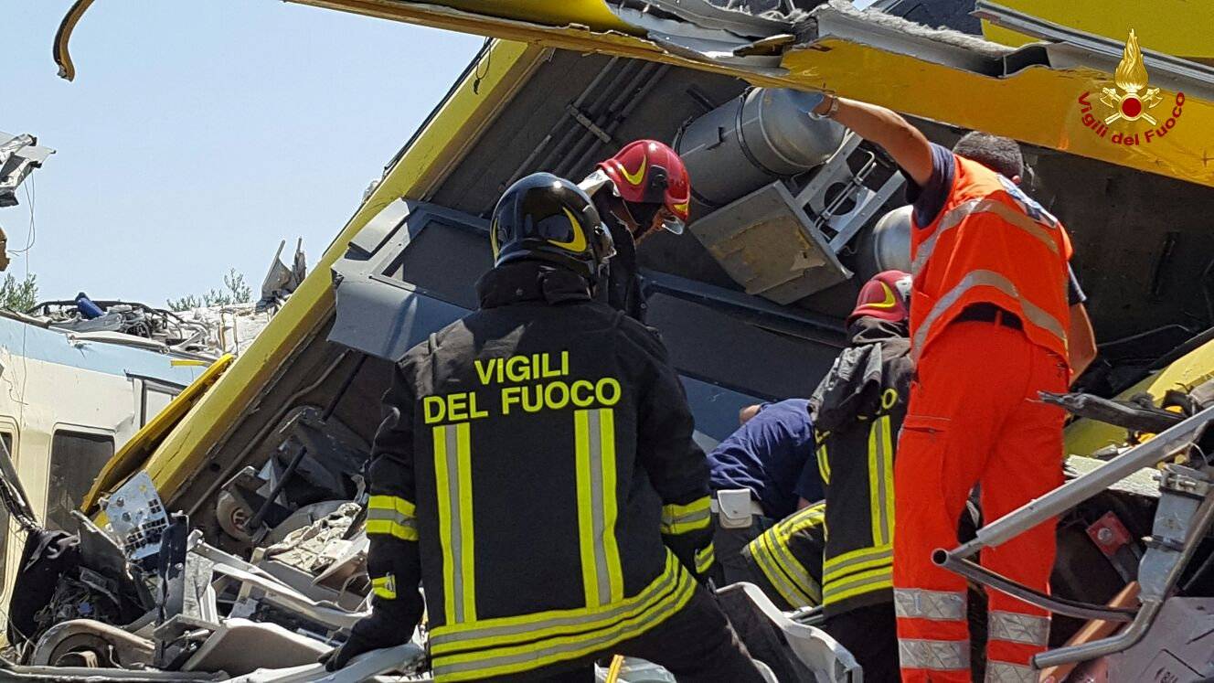 Firefighters work at the site where two passenger trains collided in the middle of an olive grove in the southern village of Corato