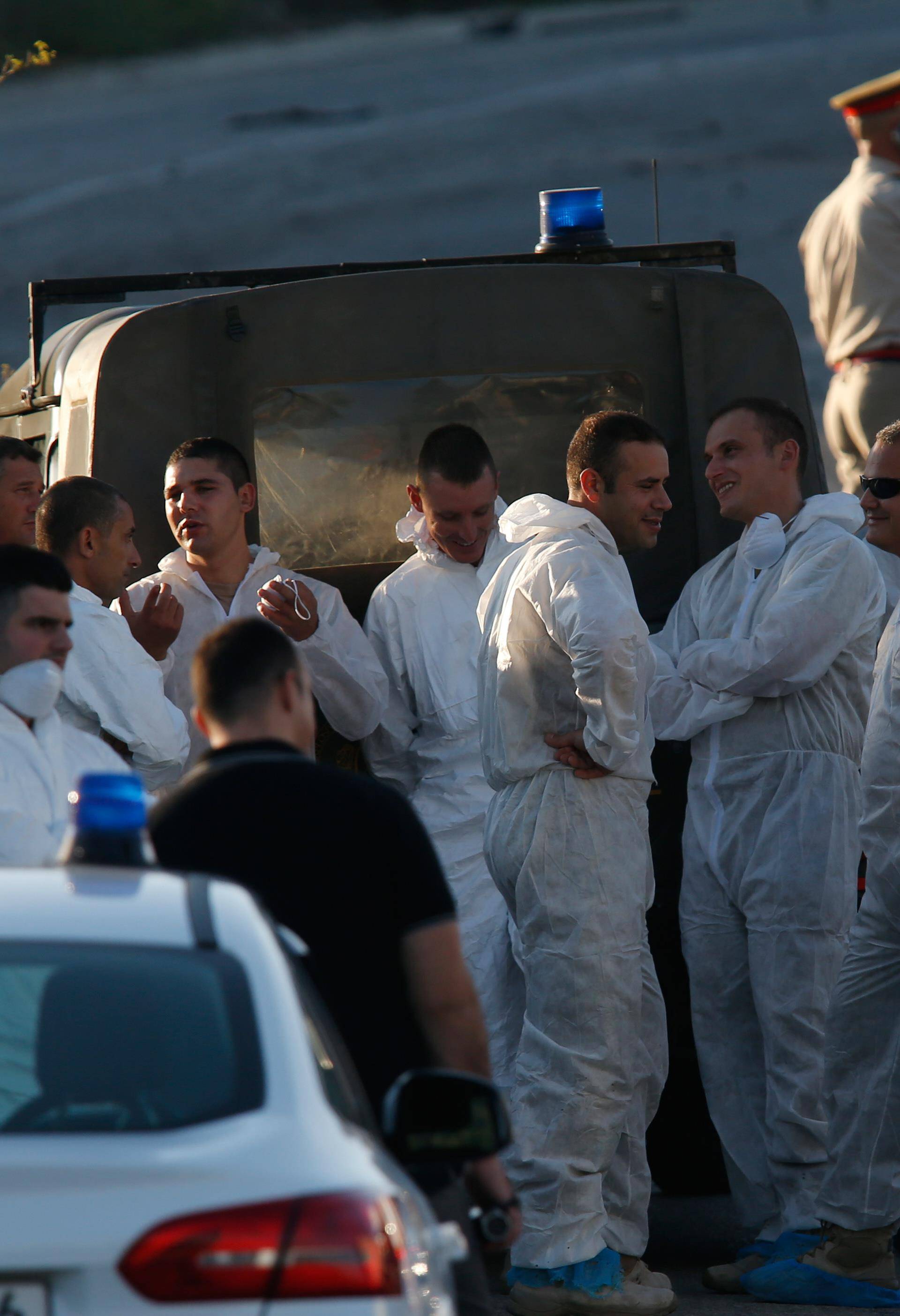 Police and forensics experts stand behind a road block after a powerful bomb blew up a car killing investigative journalist Daphne Caruana Galizia in Bidnija