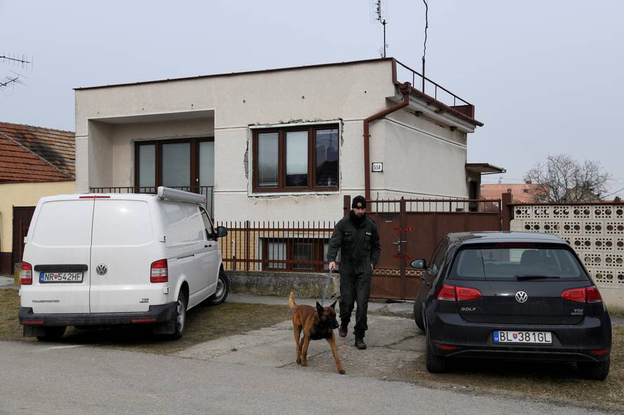 A police officer with a dog is seen near a house where Slovak investigative journalist Jan Kuciak and his girlfriend Martina Kusnirova lived and were murdered in the village of Velka Maca