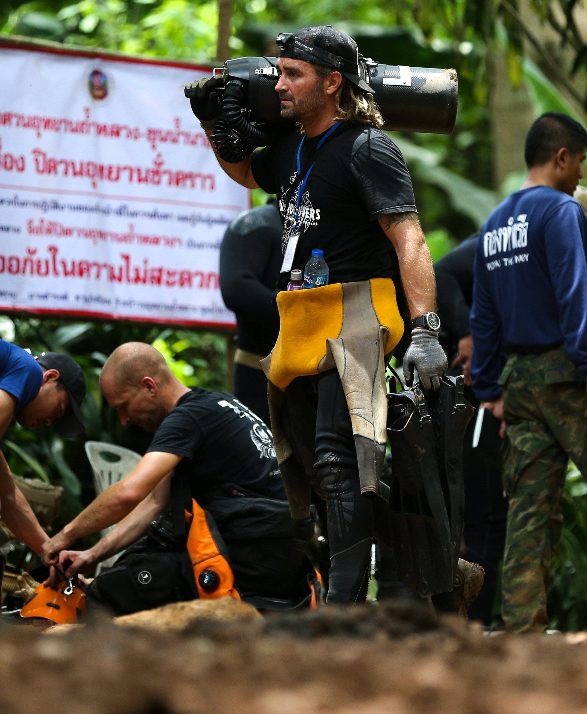 International divers carry equipments as they prepare to go in to Tham Luang cave complex, as members of an under-16 soccer team and their coach have been found alive according to local media in the northern province of Chiang Rai