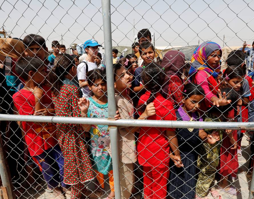 Displaced people look through barbed wire during World Refugee Day celebrations at Al-salam refugee camp in Baghdad