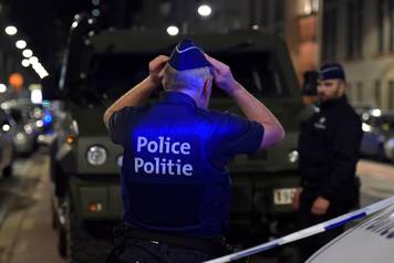 A policeman reacts on the scene after Belgian soldiers shot a man who attacked them with a knife, in Brussels