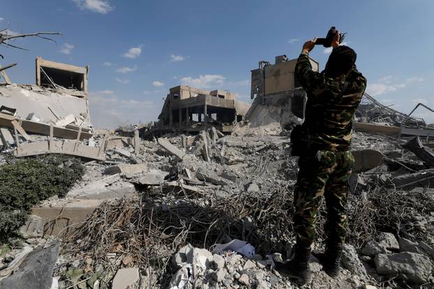 A Syrian military officer records a video inside the destroyed Scientific Research Centre in Damascus