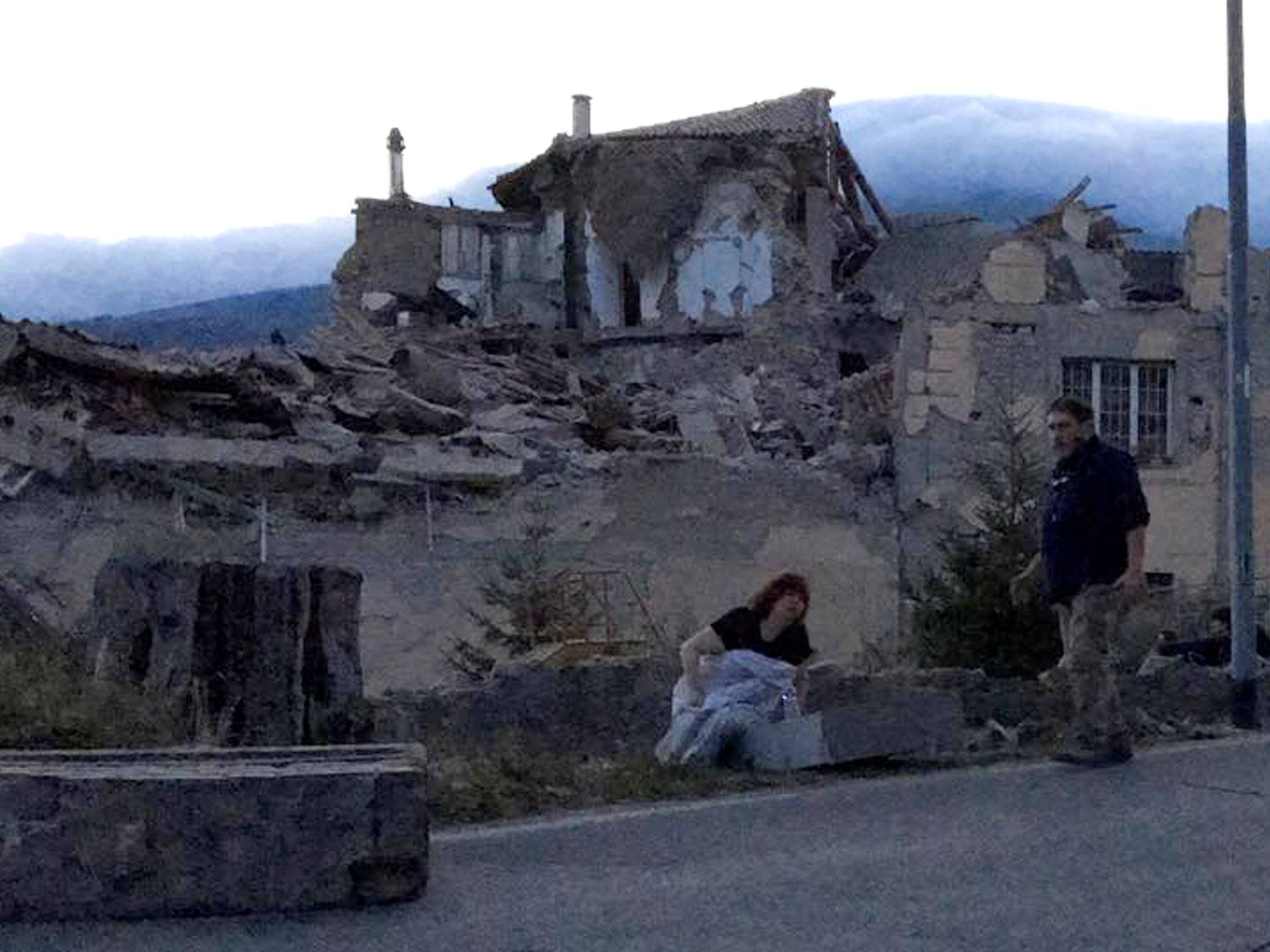 People stand by a road following a quake in Amatrice 