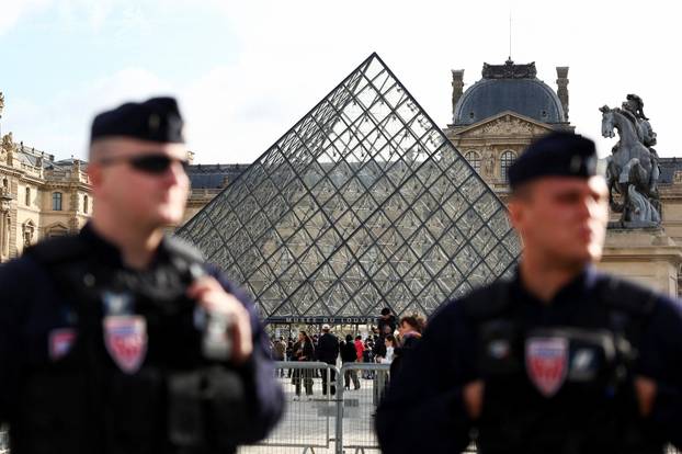 French CRS riot police stand near the glass Pyramid of the Louvre Museum