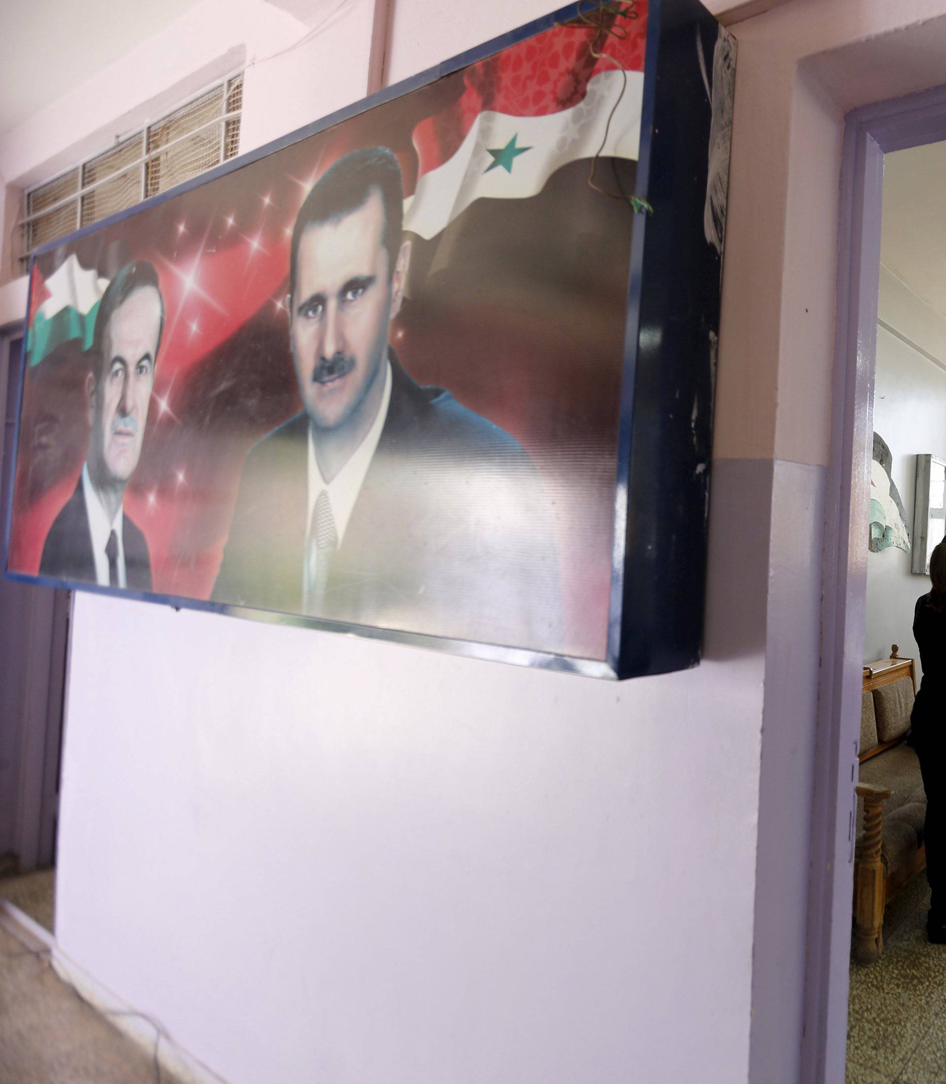 A banner showing Syria's president Bashar al-Assad and his father, former president Hafez al-Assad is seen inside a polling station during the parliamentary elections in Damascus