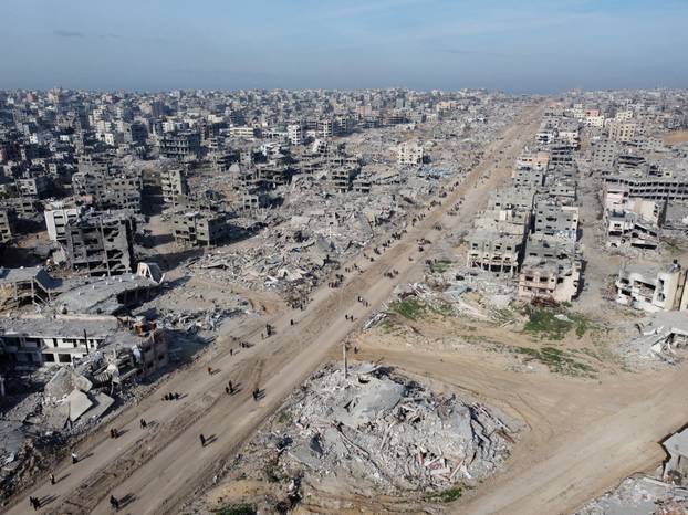 Displaced Palestinians walk past the rubble as they attempt to return to their homes, in the northern Gaza Strip