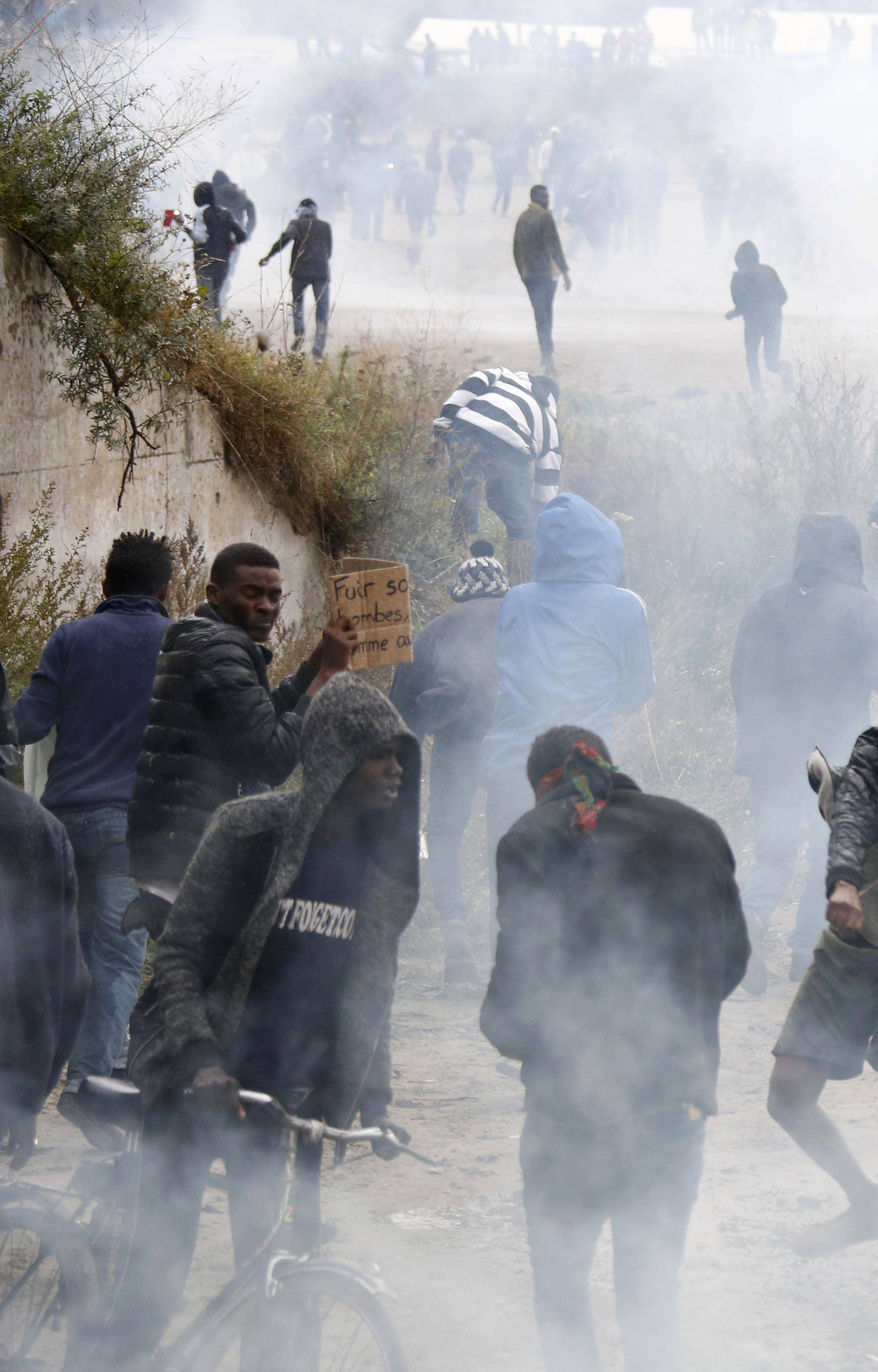 Tear gas fills the air as French riot police face off with demonstrators near the area called the "jungle" where migrants live in Calais