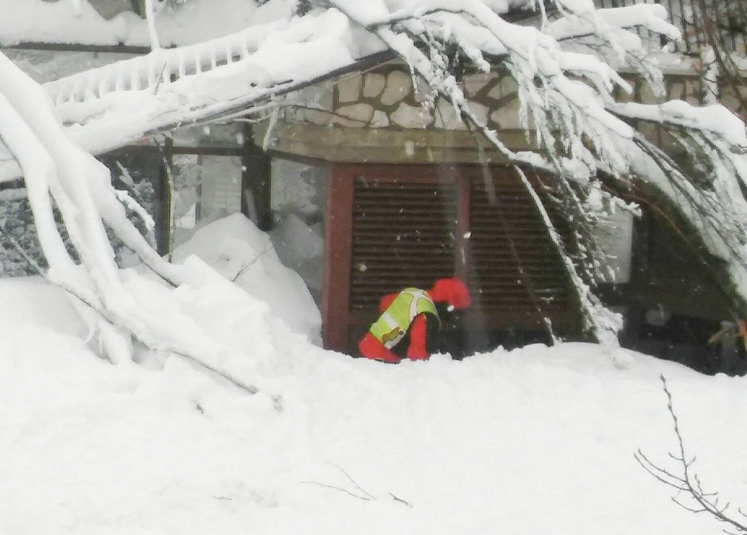A member of Lazio's Alpine and Speleological Rescue Team is seen in front of the Hotel Rigopiano in Farindola