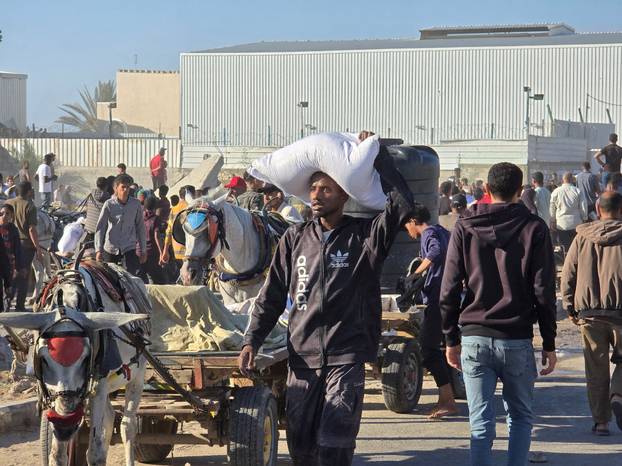 Palestinians gather at an aid distribution center in Deir Al-Balah, in the Gaza Strip