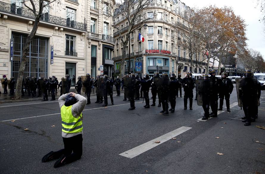 A protester wearing a yellow vest faces off with French CRS riot police during a national day of protest by the "yellow vests" movement in Paris
