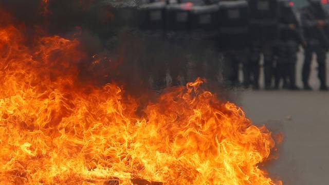 Riot policemen stand next to a barricade burned by anti-government demonstrators during a protest against the constitutional amendment PEC 55 in front of Brazil's National Congress in Brasilia