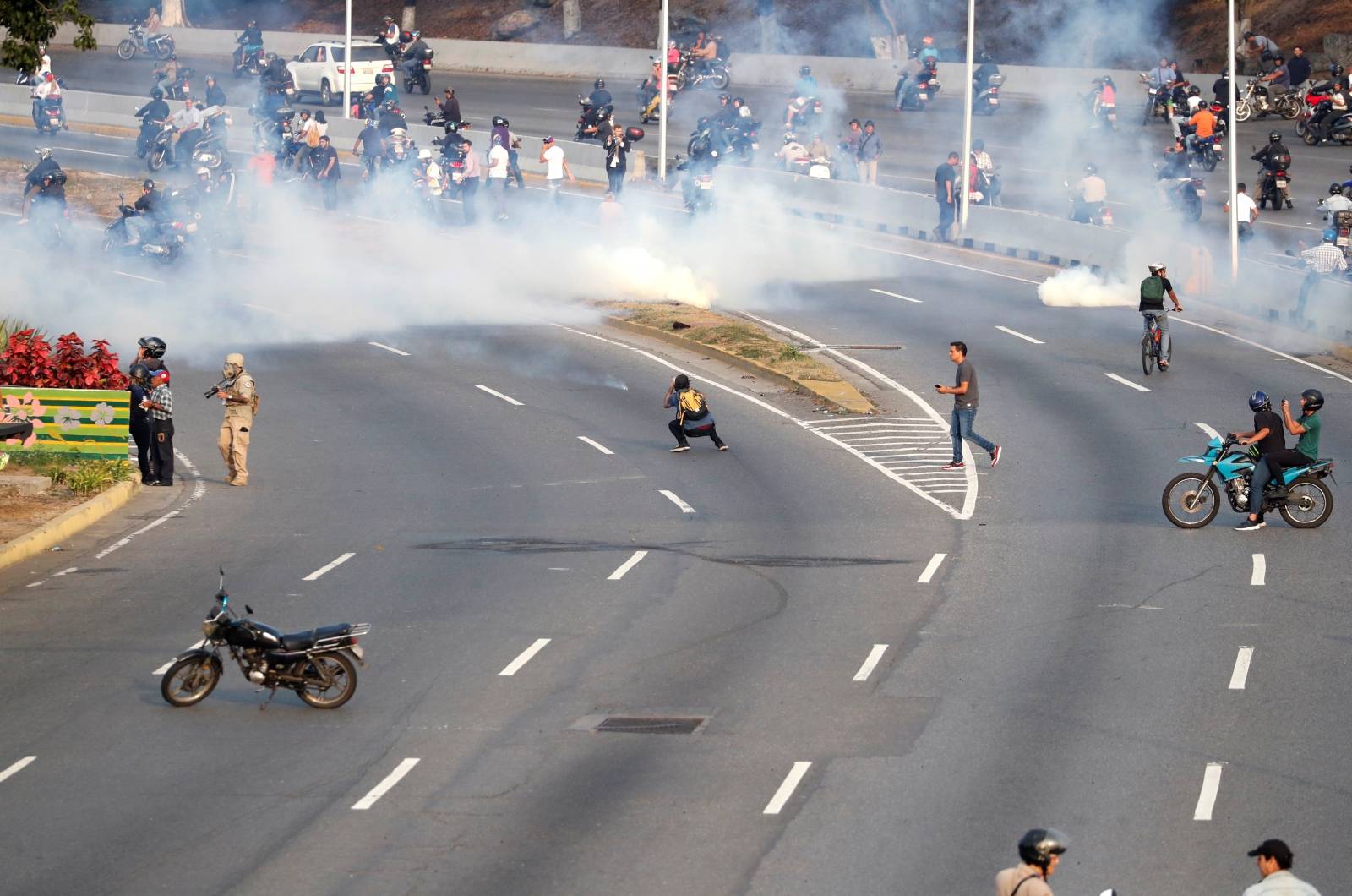 People react to tear gas near the Generalisimo Francisco de Miranda Airbase in Caracas