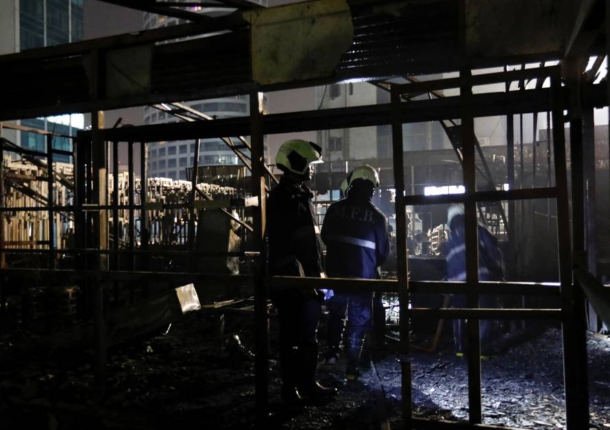 Firemen inspect the debris after a fire at a restaurant in Mumbai