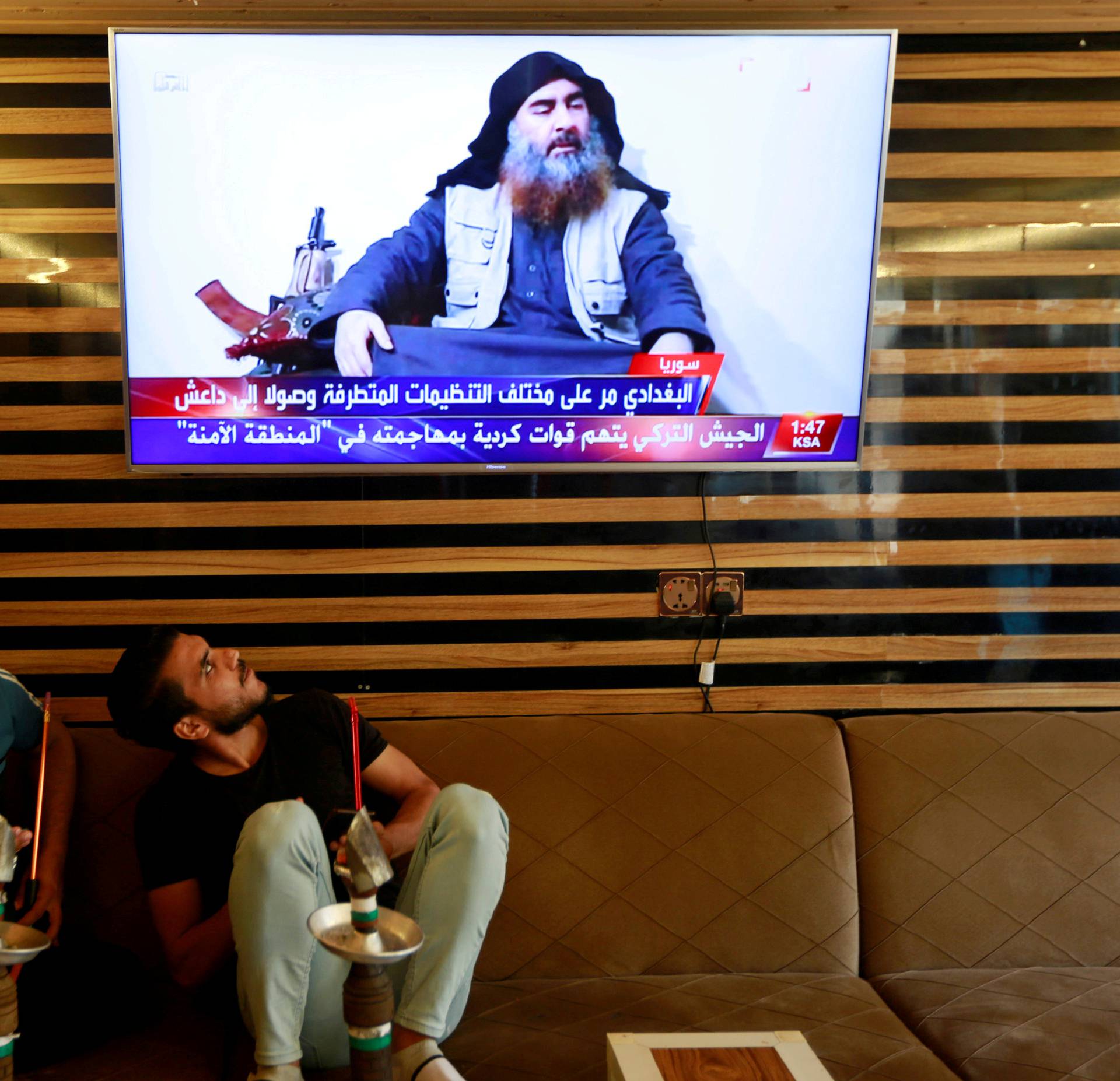 FILE PHOTO: Iraqi youth watch the news of Islamic State leader Abu Bakr al-Baghdadi death, in Najaf