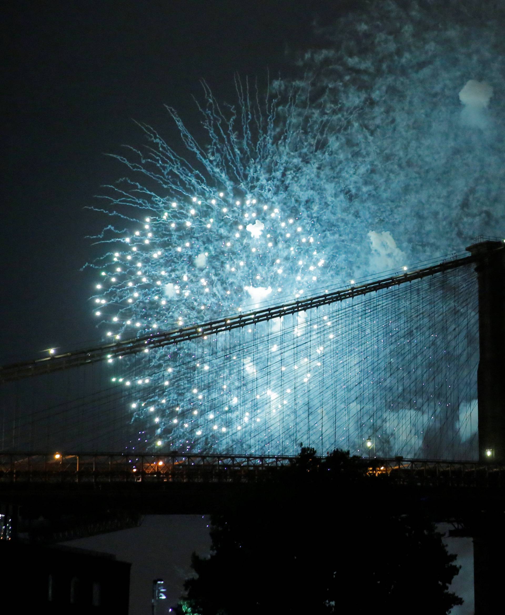 The Macy's 4th of July Fireworks explode behind the Brooklyn Bridge on the East River in New York, U.S.