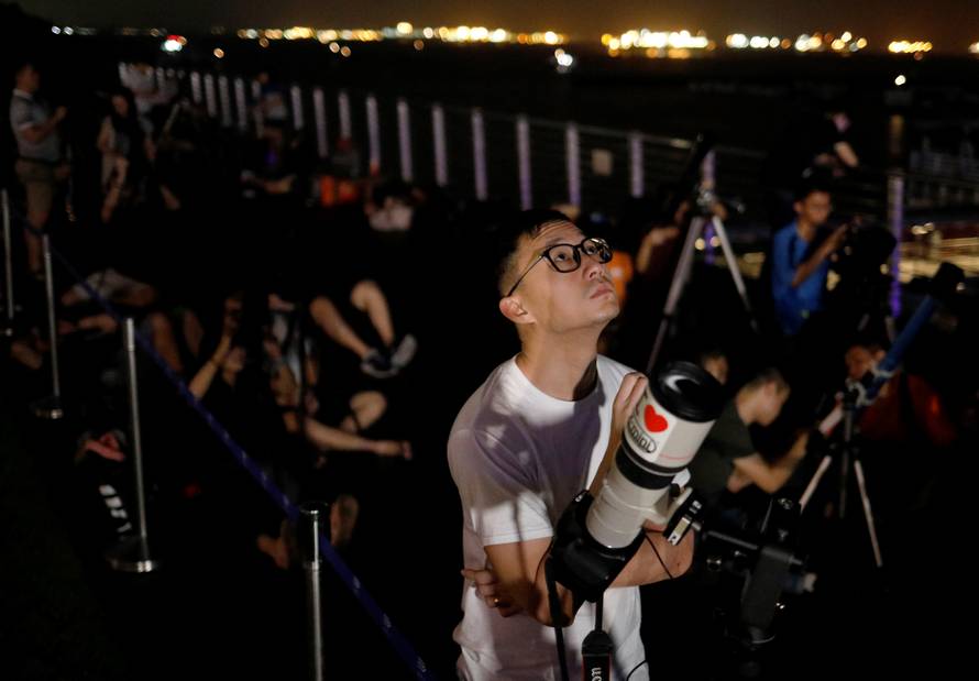 Astronomy enthusiasts wait to see the lunar eclipse of a blood moon at Marina South Pier in Singapore