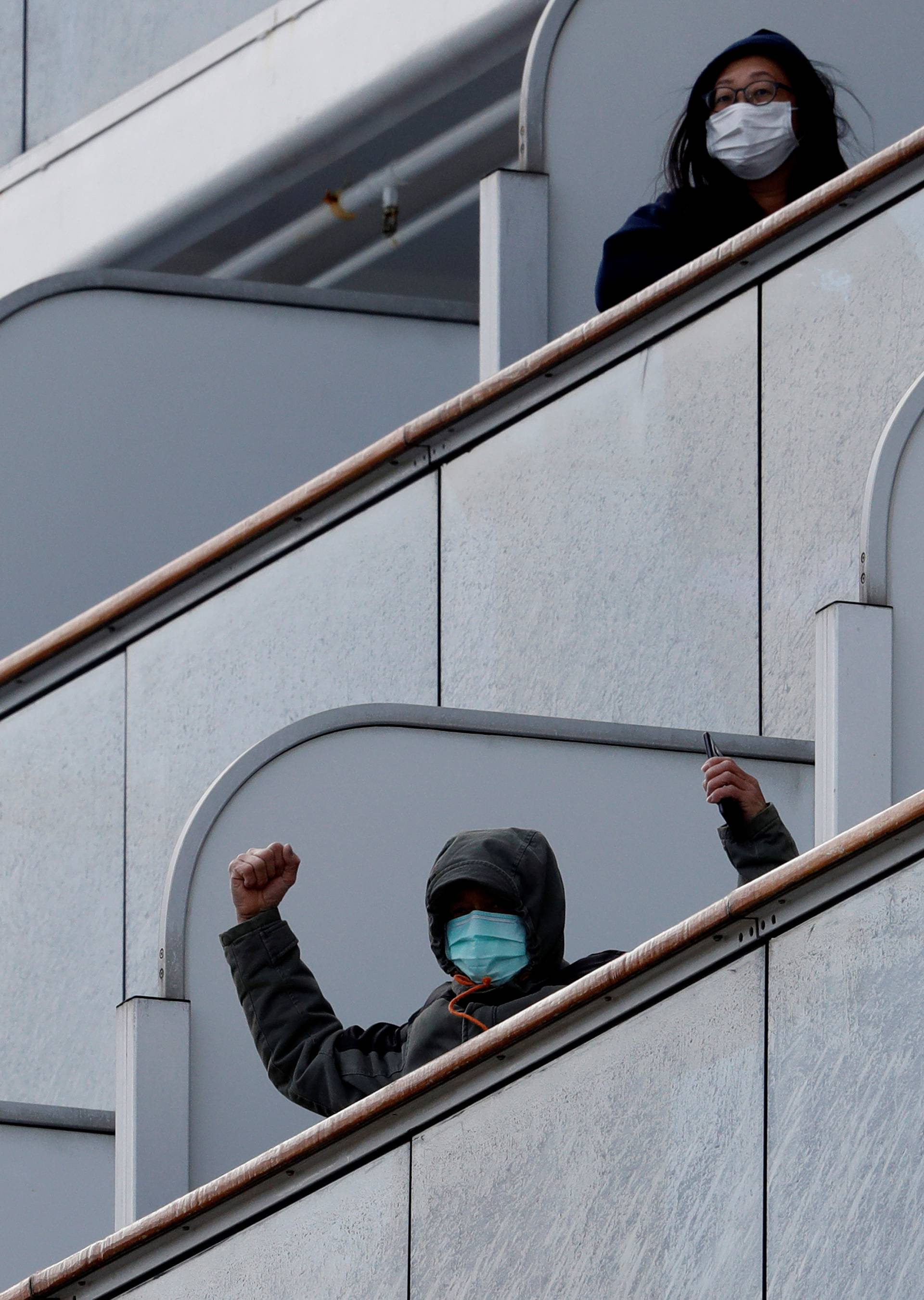 A passenger reacts as the cruise ship Diamond Princess, where 10 people on the ship had tested positive for coronavirus yesterday, arrives at Daikoku Pier Cruise Terminal in Yokohama