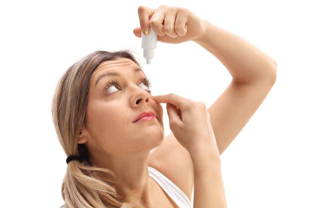 Young woman applying eye drops