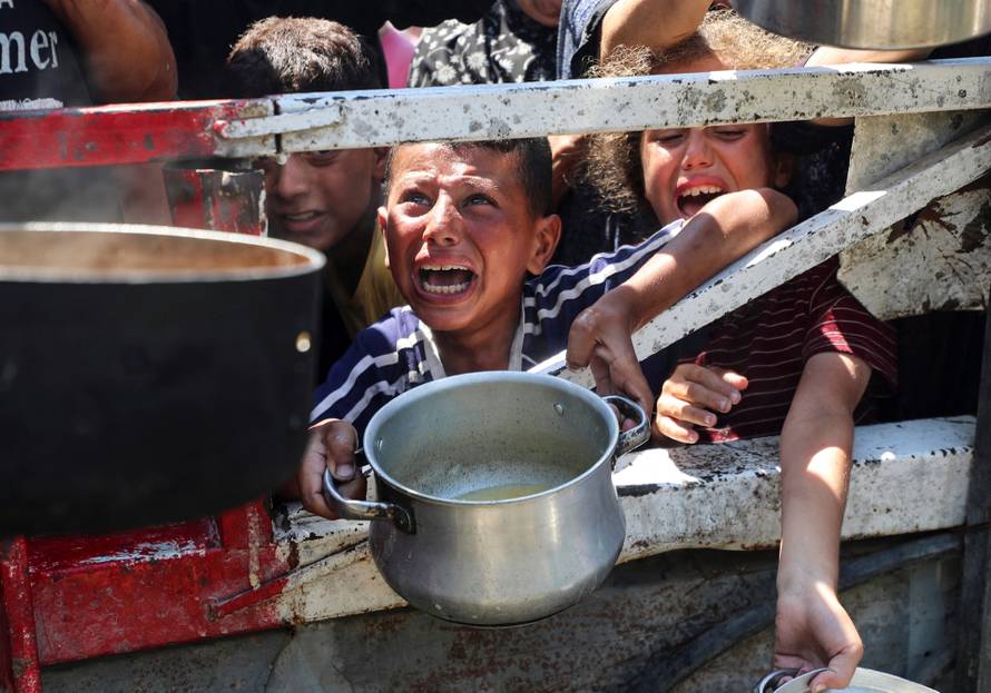 Palestinians wait to receive food from a charity kitchen, in Gaza City
