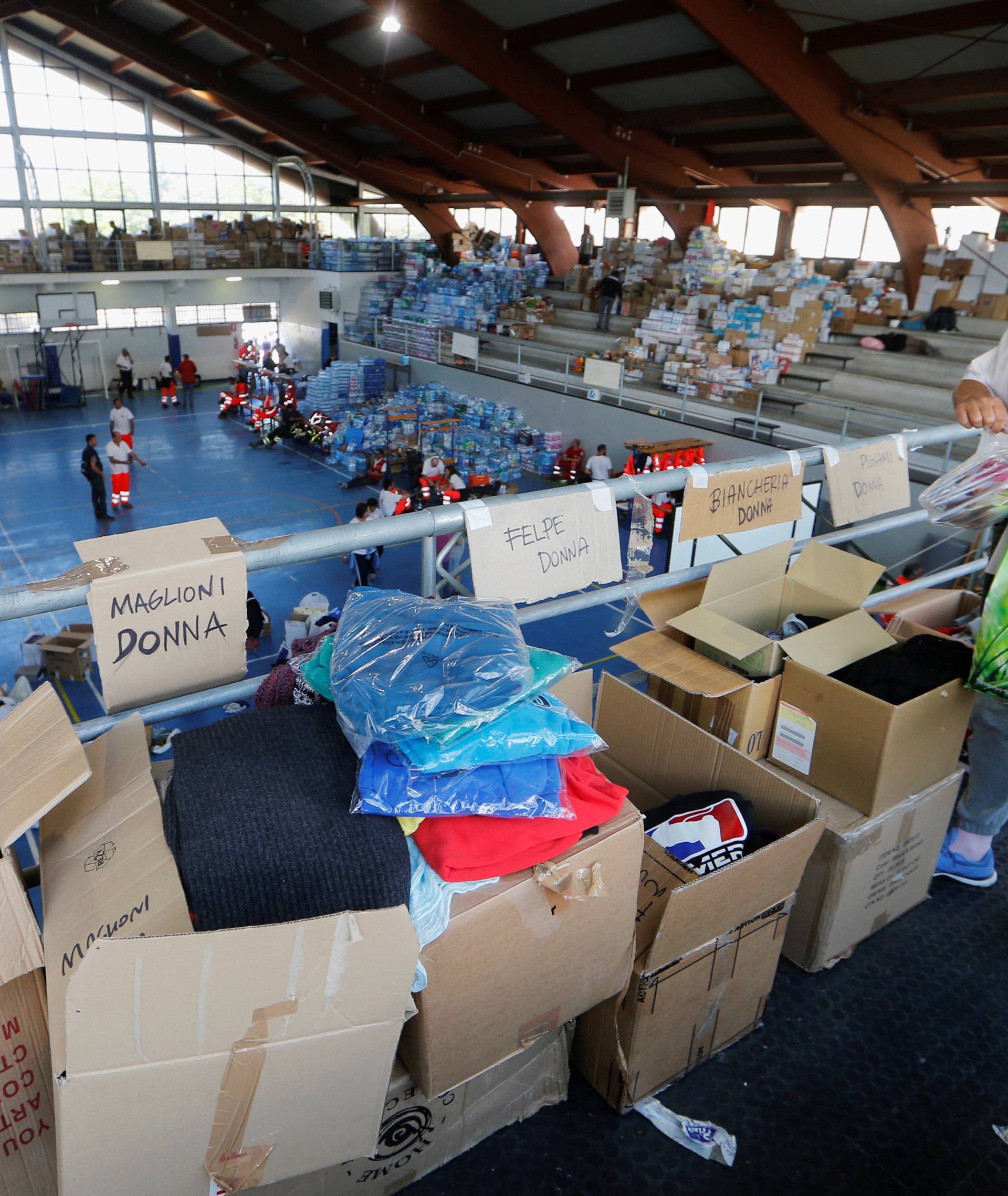 A woman gets clothes in a gym following an earthquake in Amatrice