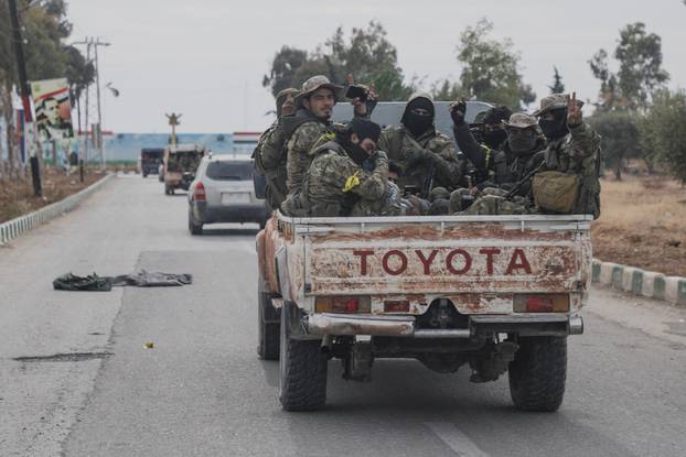 Rebel fighters sit on a vehicle in Homs countryside