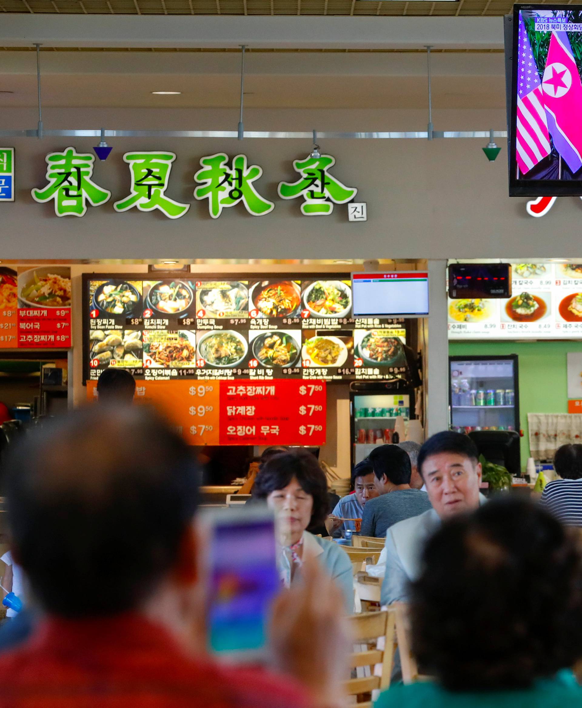 People watch from a shopping mall food court  in the Los Angeles neighborhood of Koreatown as Singapore hosts a summit between U.S. President Donald Trump and North Korean leader Kim Jong Un in Los Angeles