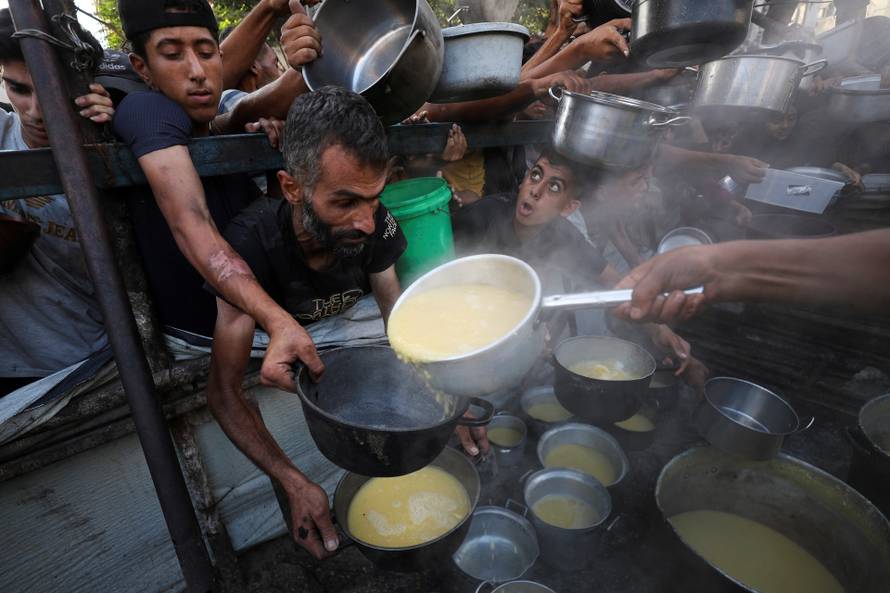 Palestinians receive food from a charity kitchen, amid a hunger crisis, in Gaza City