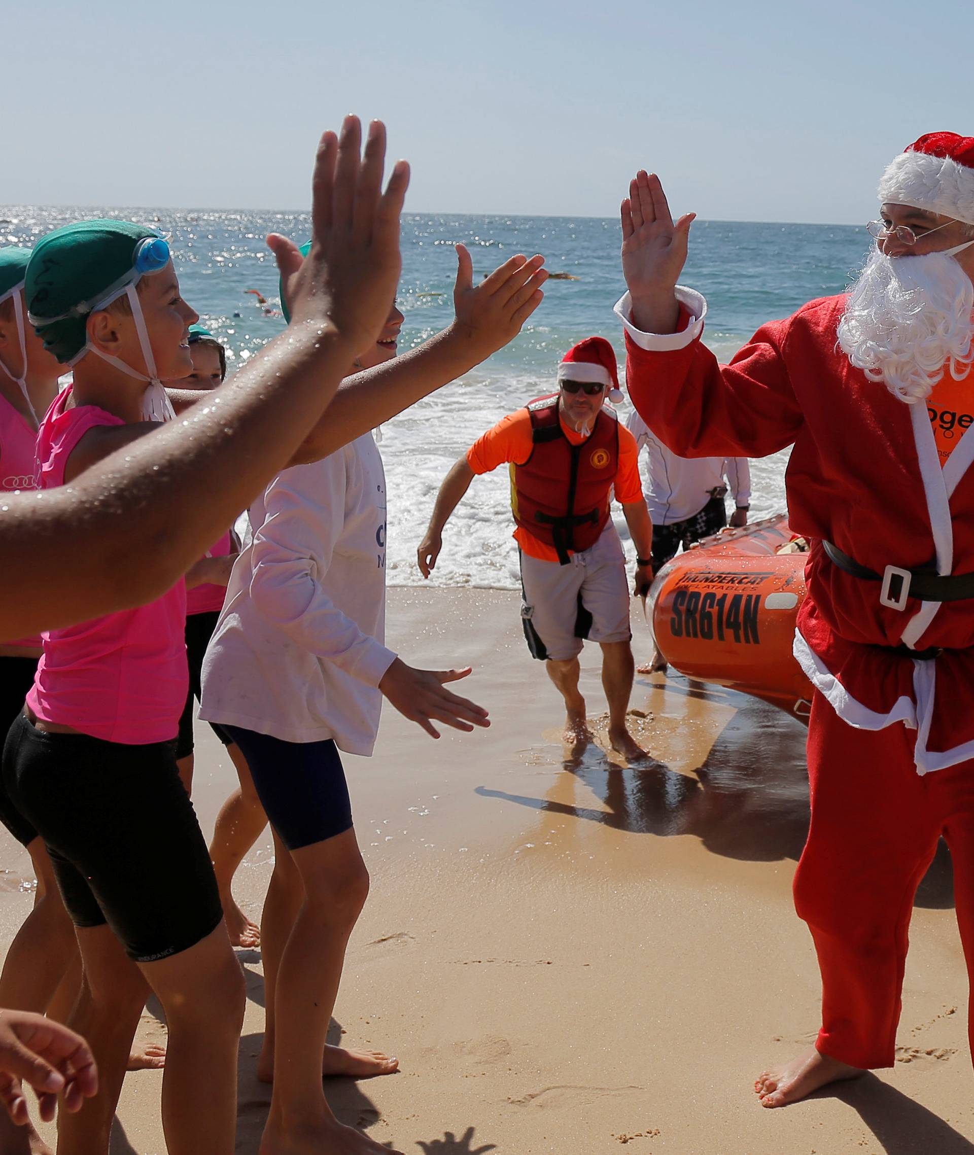 A surf life saver dressed as Santa Claus arrives to deliver gifts to children at Sydney's Coogee beach
