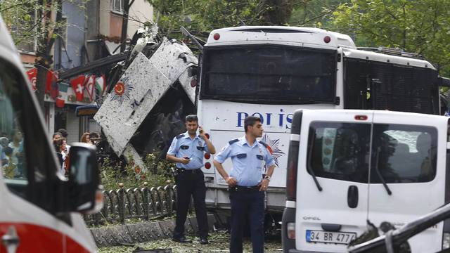A policeman uses his phone near a Turkish police bus which was targeted in a bomb attack in a central Istanbul district