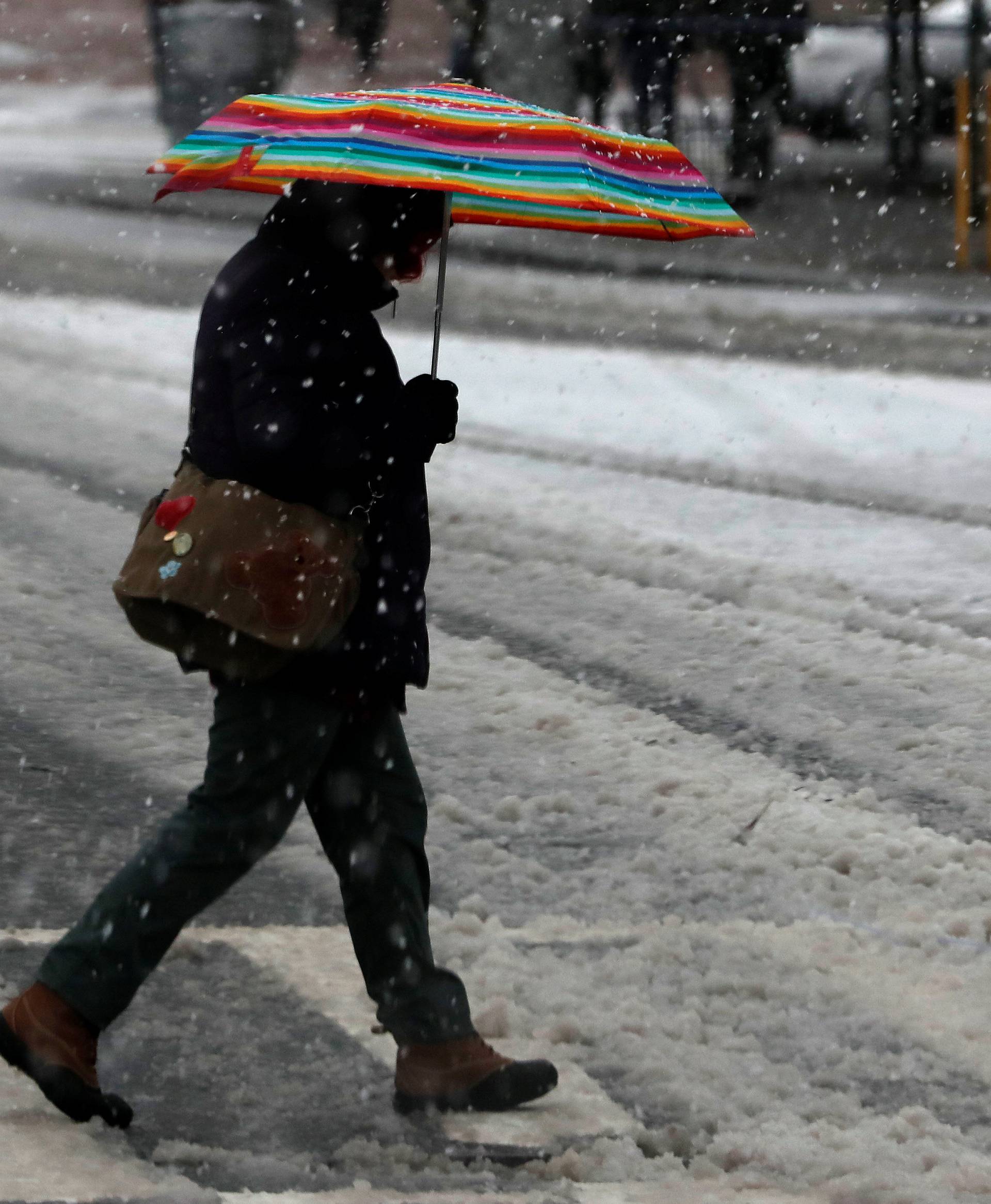 A woman crosses Broadway during a snowstorm in upper Manhattan in New York City