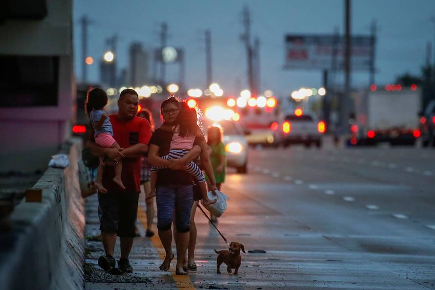 The Duong family, with children, parents and dog in tow, walks along Interstate 45 while escaping flood waters from Tropical Storm Harvey in Houston