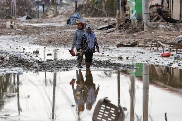 Women walk in an area affected by a deadly flash flood following heavy rains in Aceh Tamiang regency