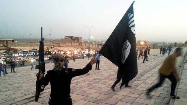 FILE PHOTO: ISIL fighter holds a flag and a weapon on a street in Mosul