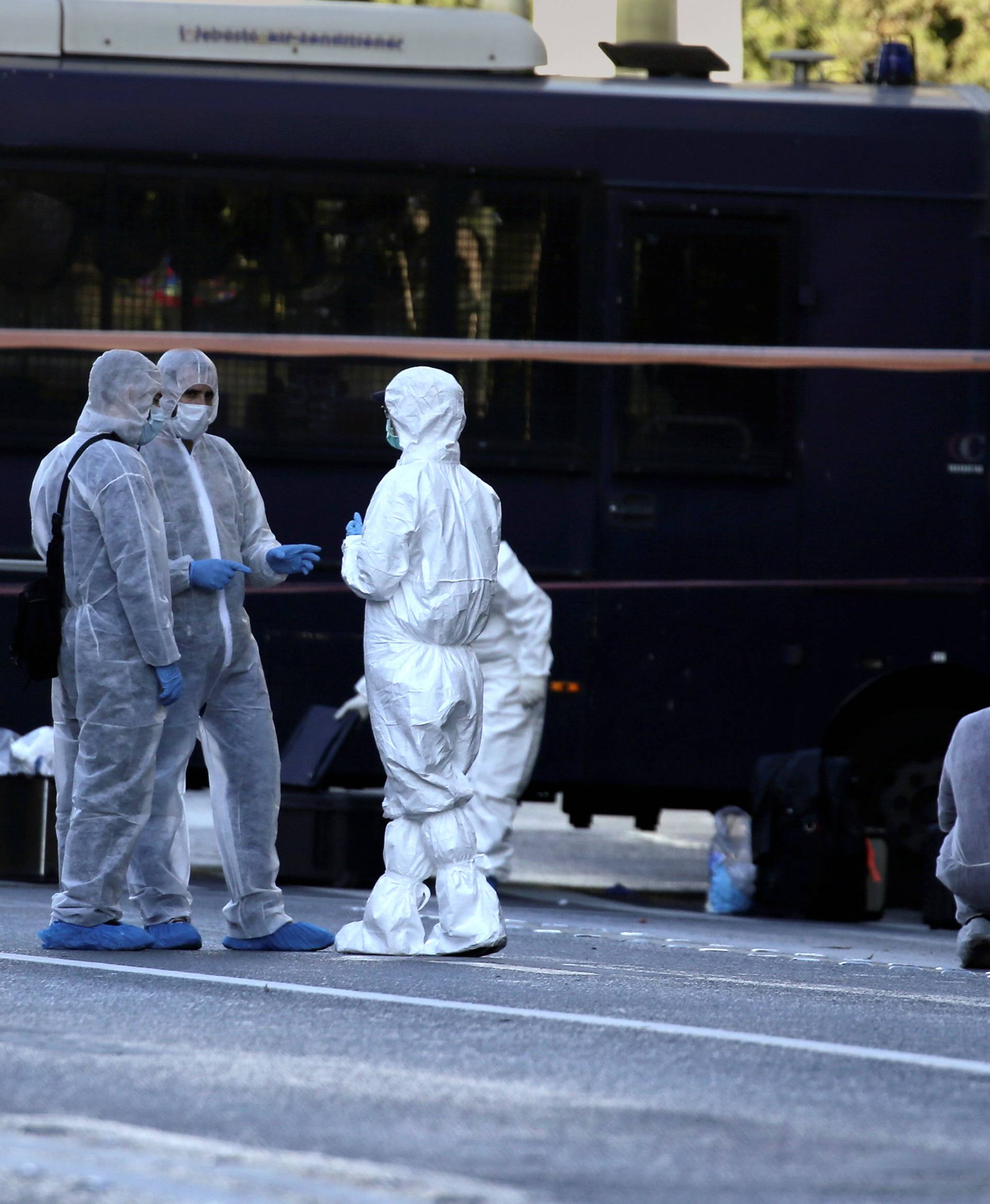 Forensics experts search for evidence outside the French embassy, where unidentified attackers threw an explosive device causing a small blast, in Athens