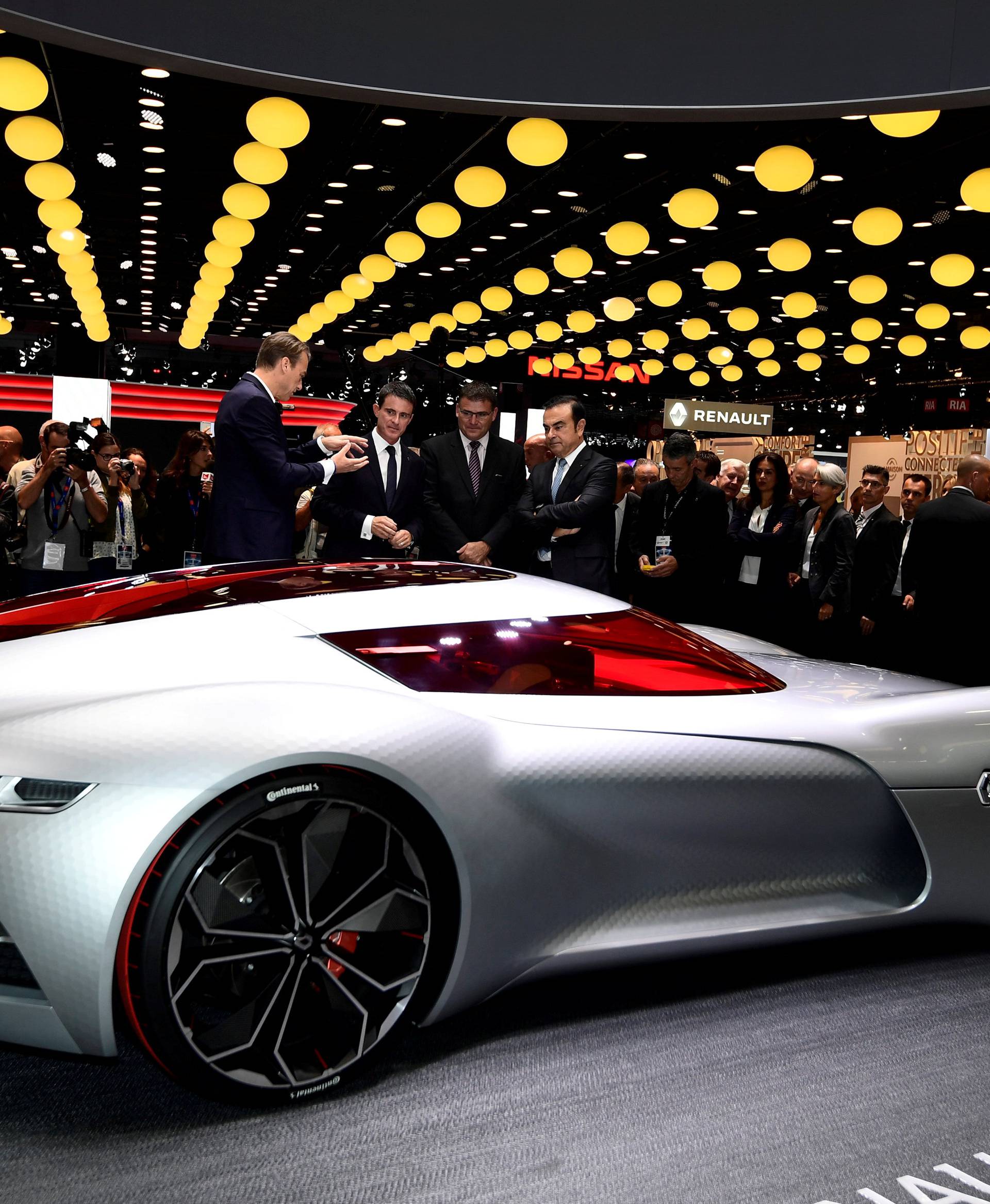 Carlos Ghosn, Chairman and CEO of the Renault-Nissan Alliance, and French Prime Minister Manuel Valls listen to an explication as they look at the Renault concept car "Trezor" at the Paris auto show, in Paris
