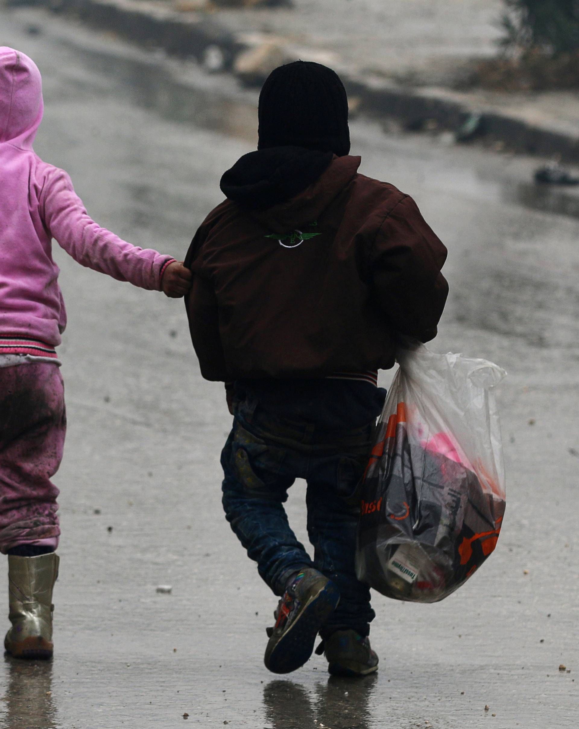 Children walk together as they flee deeper into the remaining rebel-held areas of Aleppo