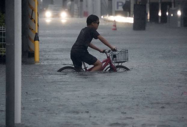 A boy cycles through a flooded street as Typhoon Dujuan brings heavy rain, in Ichikawa