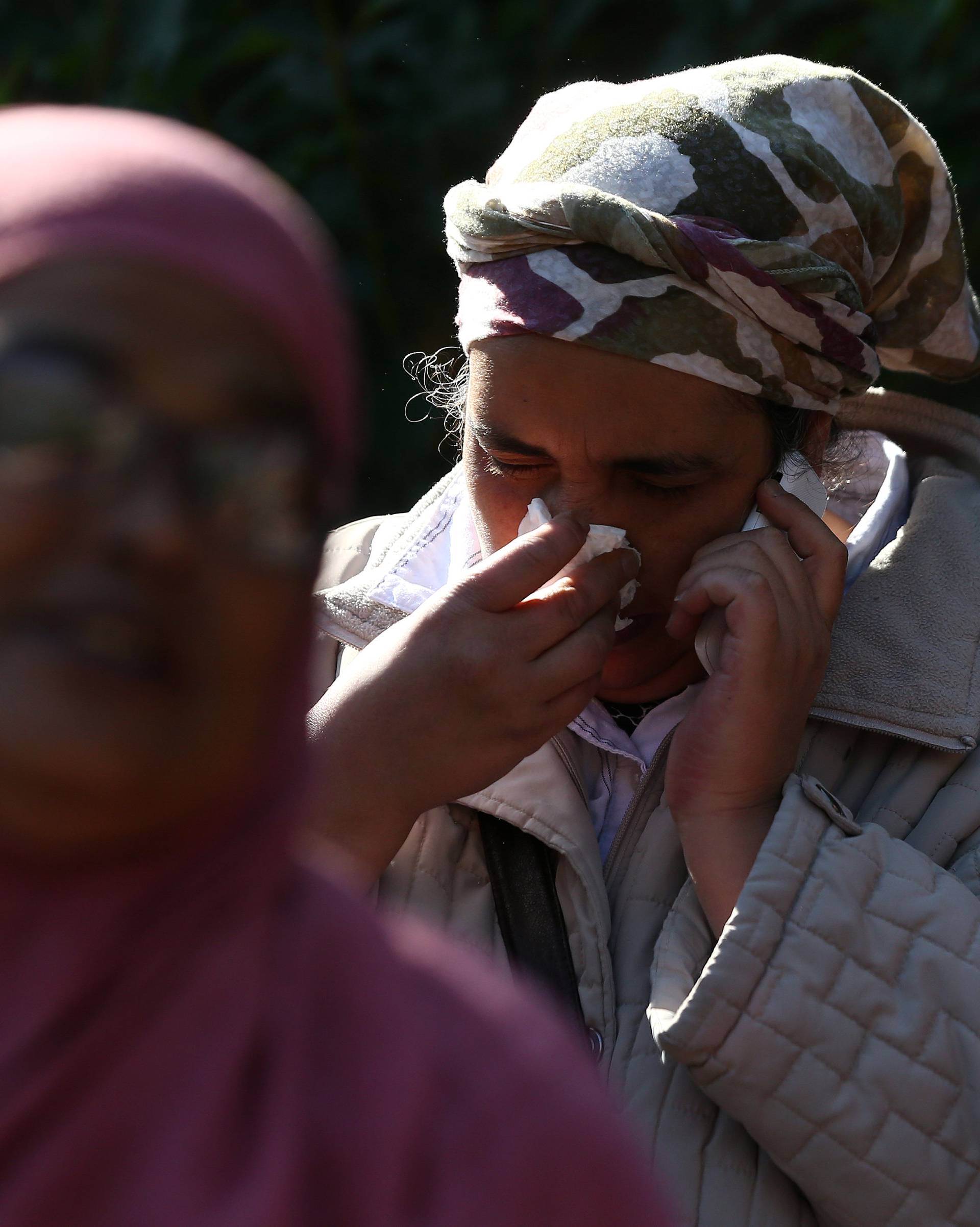 A woman speaks on a mobile phone near a tower block that was severly damaged by a serious fire, in north Kensington, West London