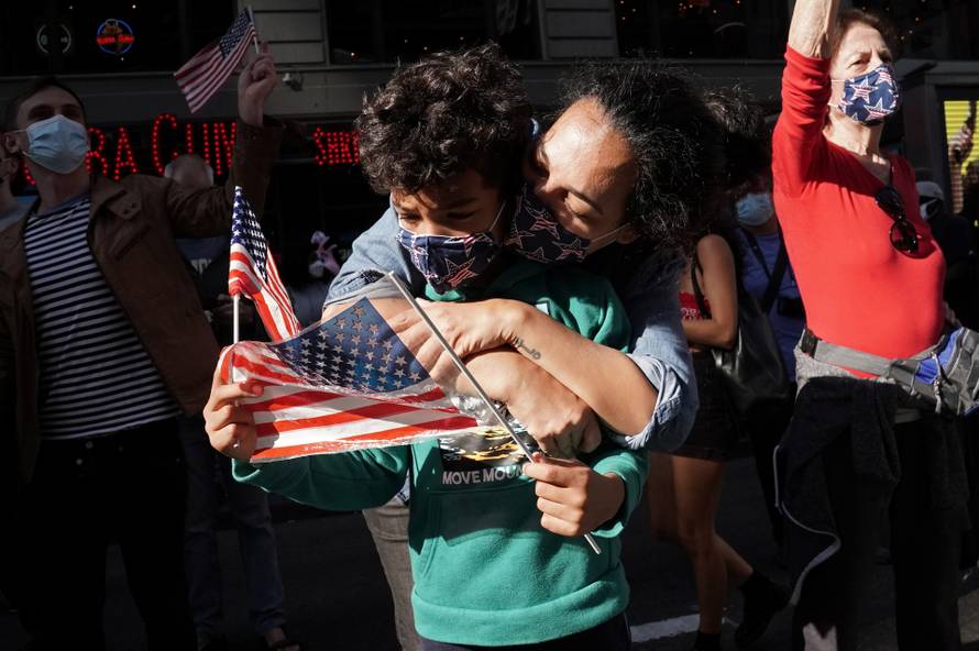 People react as media announce that Democratic U.S. presidential nominee Joe Biden has won the 2020 U.S. presidential election, on Times Square in New York City