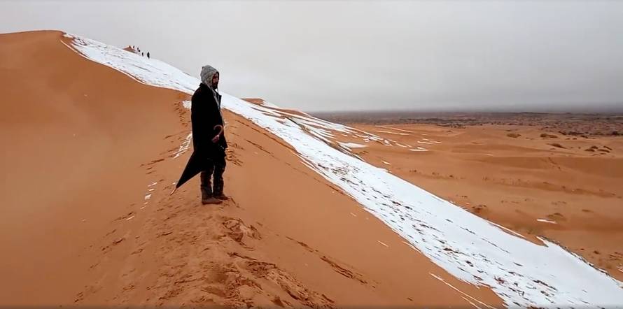 A man looks at at a snow-covered slope in the Sahara, Ain Sefra
