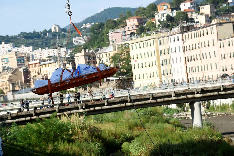Rescue workers recover a body at the site of the collapsed Morandi Bridge in the port city of Genoa