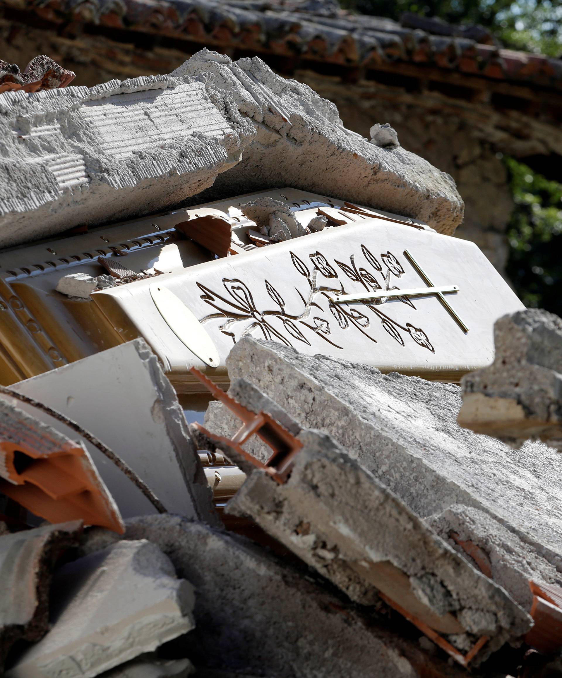 A coffin covered by debris is seen in a cemetery following an earthquake at Sant' Angelo near Amatrice