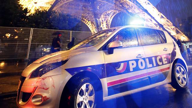 A police car is seen parked in front of the Eiffel Tower in Paris