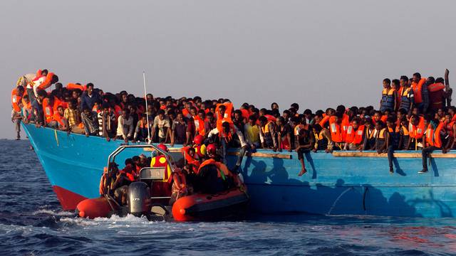 A rescue boat of the Spanish NGO Proactiva approaches an overcrowded wooden vessel with migrants from Eritrea, off the Libyan coast in Mediterranean Sea