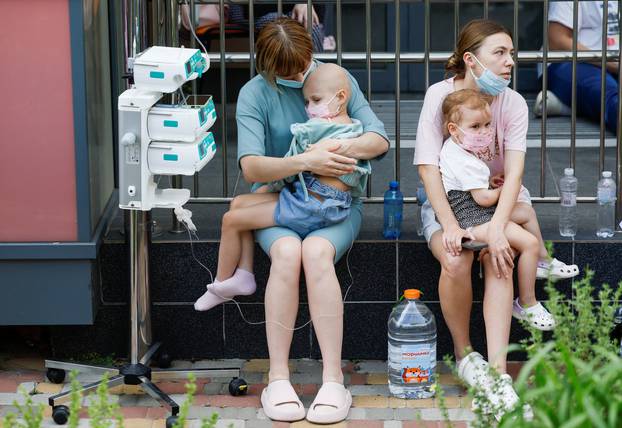 Women hold patients at Ohmatdyt Children's Hospital that was damaged during Russian missile strikes, in Kyiv