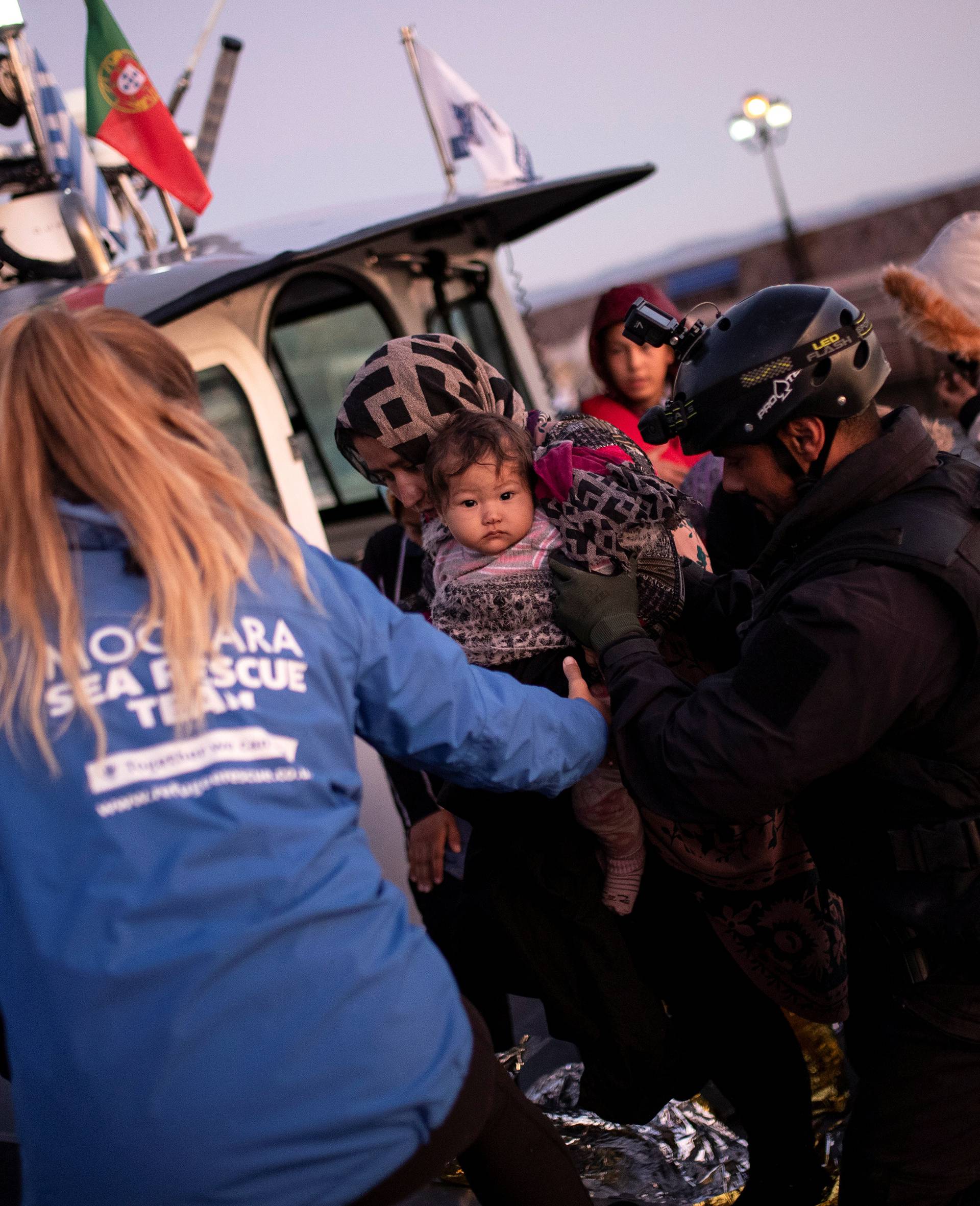 A migrant holding a baby is helped to disembark a Frontex patrol vessel carrying migrants rescued at open sea, at the port of Skala Sikamias