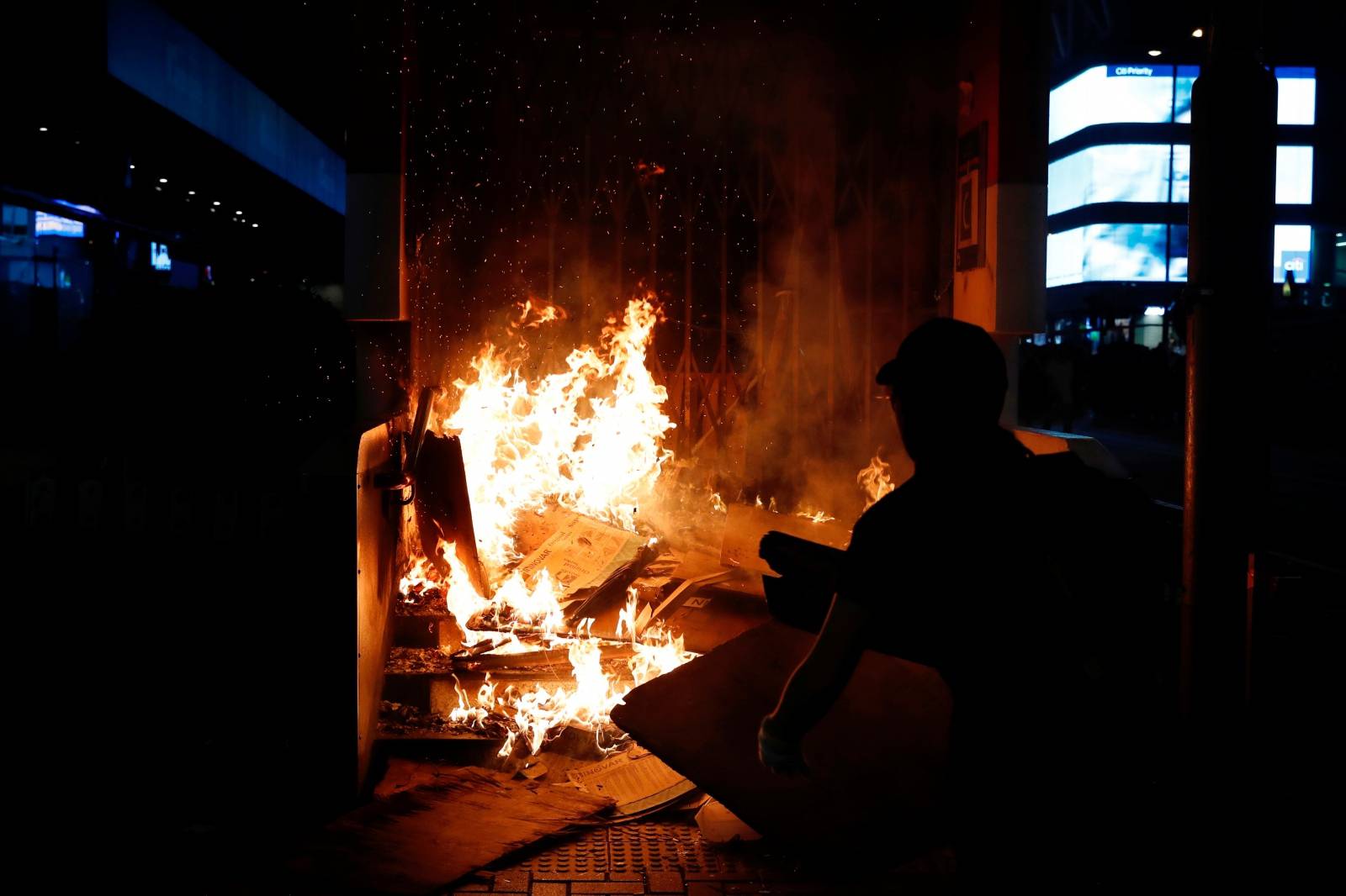 An anti-government protester wears a mask as he sets a fire outside Mong Kok Mass Transit Railway (MTR) station during a demonstration after government's ban on face masks under emergency law, at Mong Kok